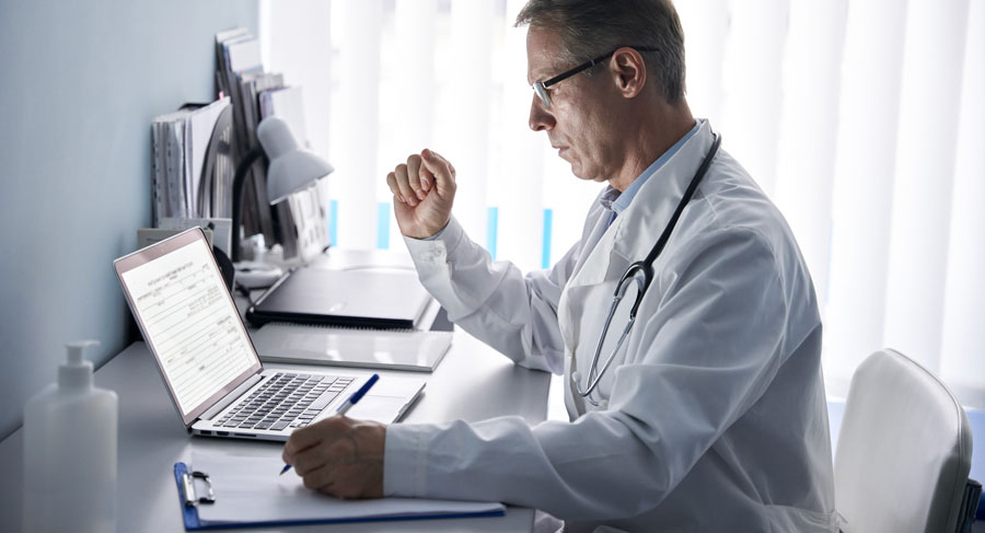 serious-older-doctor-using-laptop-computer-in-medical